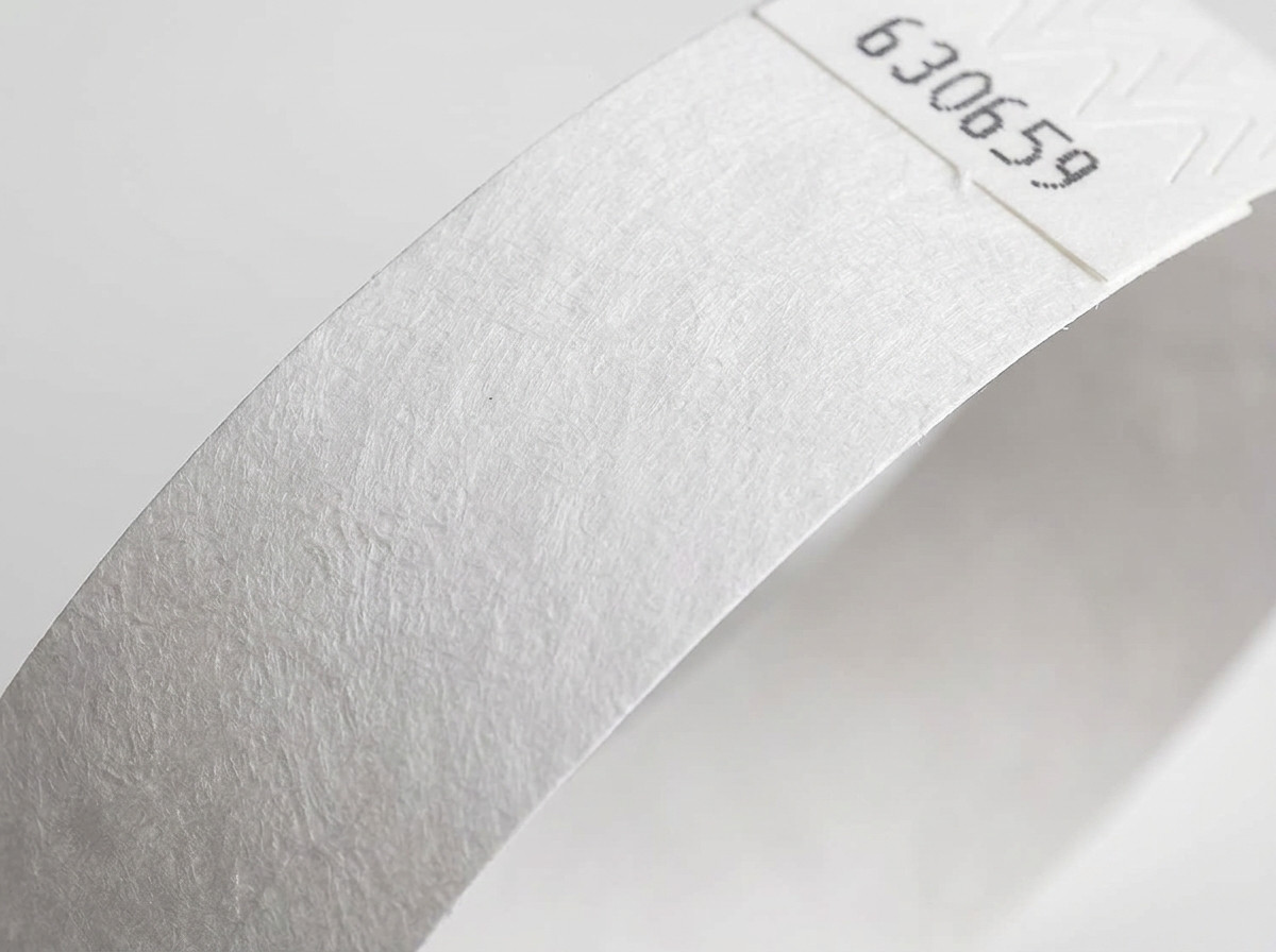 Prim-plan pe suprafata netesuta a unui bracelete Tyvek alb, aratand textura caracteristica a polietilenei de inalta densitate